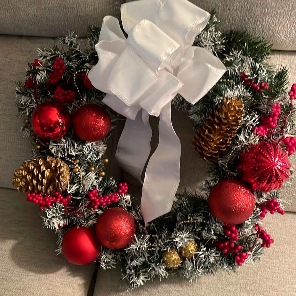 Christmas wreath decorated w/ornaments, gold pine cones w/large white bow